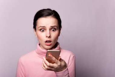 Gri arka planda telefonla konuşan pembe balıkçı yakalı güzel bir kız.