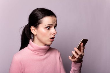 Gri arka planda telefonla konuşan pembe balıkçı yakalı güzel bir kız.