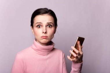 Gri arka planda telefonla konuşan pembe balıkçı yakalı güzel bir kız.