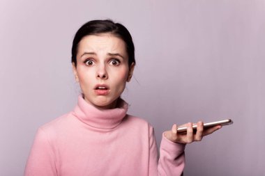 Gri arka planda telefonla konuşan pembe balıkçı yakalı güzel bir kız.