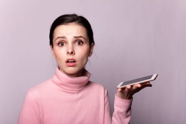 Gri arka planda telefonla konuşan pembe balıkçı yakalı güzel bir kız.