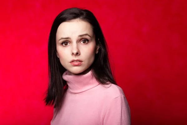 beautiful girl in a pink turtleneck on a red background