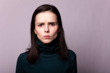 Gri bir fotoğrafta yeşil balıkçı yakalı güzel bir kız.