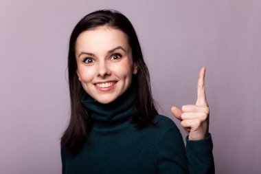 Gri bir fotoğrafta yeşil balıkçı yakalı güzel bir kız.