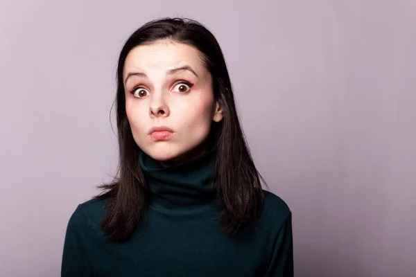 beautiful girl in a green turtleneck on a gray photo