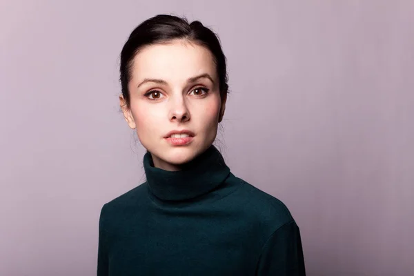 beautiful girl in a green turtleneck on a gray photo