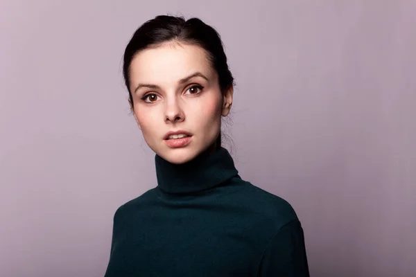 beautiful girl in a green turtleneck on a gray photo