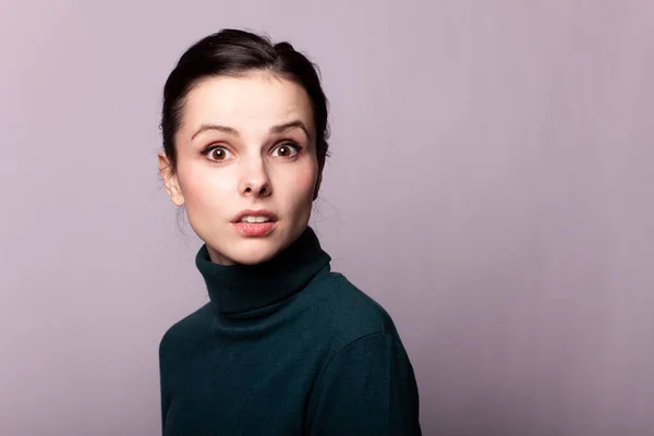 beautiful girl in a green turtleneck on a gray photo