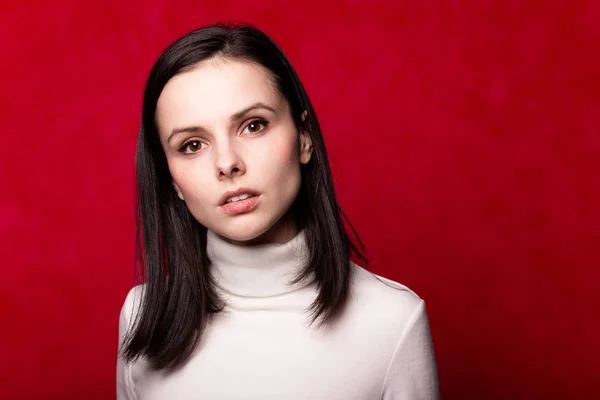 girl in a white turtleneck, portrait on a red background