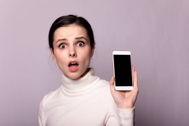 Beyaz balıkçı yakalı bir kız telefonla konuşuyor, gri arka planda bir portre.