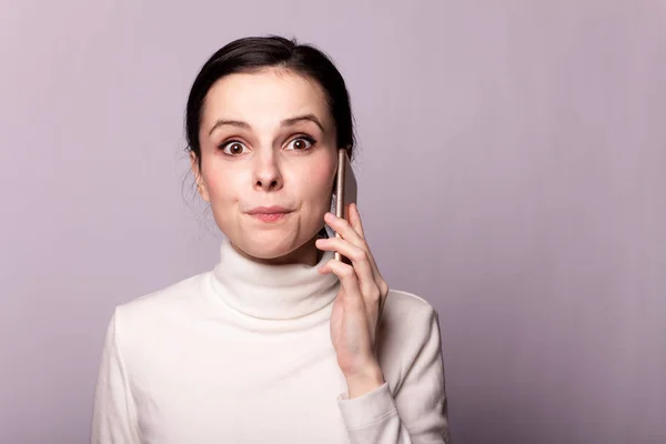 Meisje Een Witte Coltrui Praten Telefoon Portret Een Grijze Achtergrond — Stockfoto