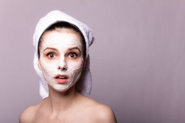 Kafasında beyaz havluyla yüzünde maske olan bir kız.