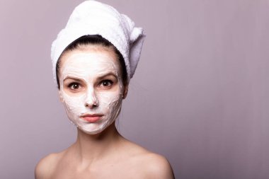 Kafasında beyaz havluyla yüzünde maske olan bir kız.