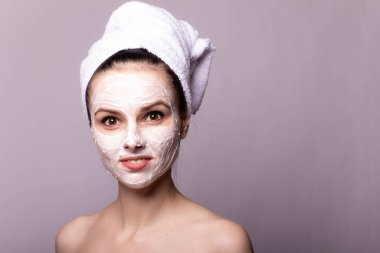 Kafasında beyaz havluyla yüzünde maske olan bir kız.