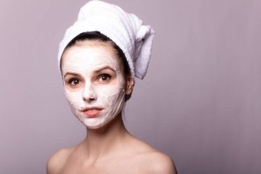 Kafasında beyaz havluyla yüzünde maske olan bir kız.