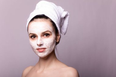 Kafasında beyaz havluyla yüzünde maske olan bir kız.