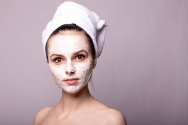 Kafasında beyaz havluyla yüzünde maske olan bir kız.