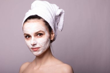 Kafasında beyaz havluyla yüzünde maske olan bir kız.
