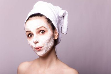 Kafasında beyaz havluyla yüzünde maske olan bir kız.