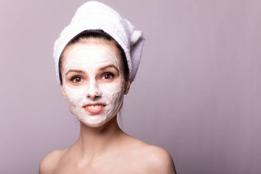 Kafasında beyaz havluyla yüzünde maske olan bir kız.