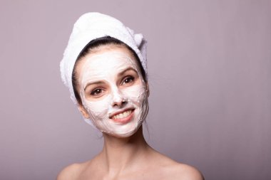 Kafasında beyaz havluyla yüzünde maske olan bir kız.