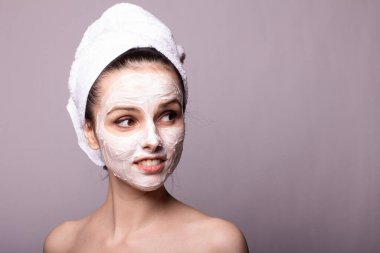 Kafasında beyaz havluyla yüzünde maske olan bir kız.