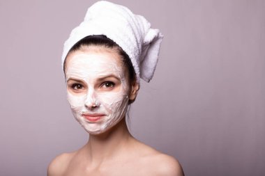 Kafasında beyaz havluyla yüzünde maske olan bir kız.