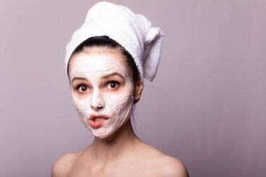 Kafasında beyaz havluyla yüzünde maske olan bir kız.
