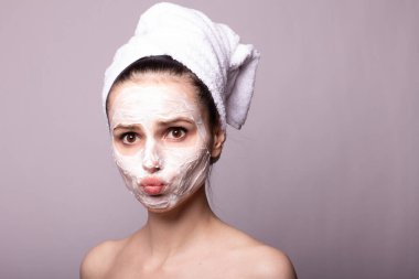 Kafasında beyaz havluyla yüzünde maske olan bir kız.