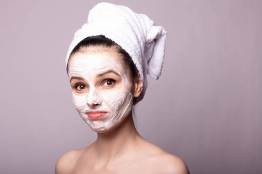 Kafasında beyaz havluyla yüzünde maske olan bir kız.