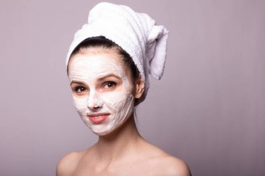 Kafasında beyaz havluyla yüzünde maske olan bir kız.
