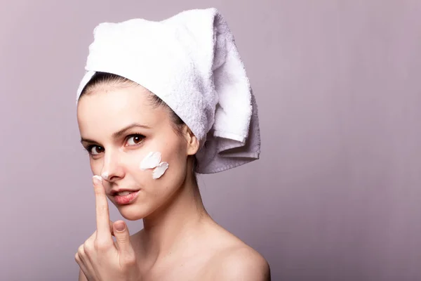 Menina Com Uma Toalha Branca Cabeça Creme Seu Rosto Mão — Fotografia de Stock