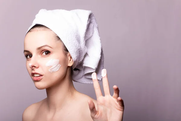 Menina Com Uma Toalha Branca Cabeça Creme Seu Rosto Mão — Fotografia de Stock