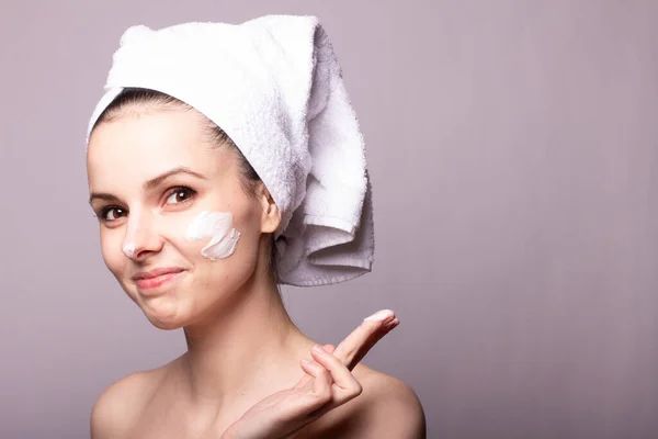 Menina Com Uma Toalha Branca Cabeça Creme Seu Rosto Mão — Fotografia de Stock