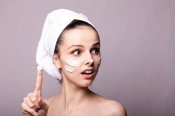 Menina Com Uma Toalha Branca Cabeça Creme Seu Rosto Mão — Fotografia de Stock