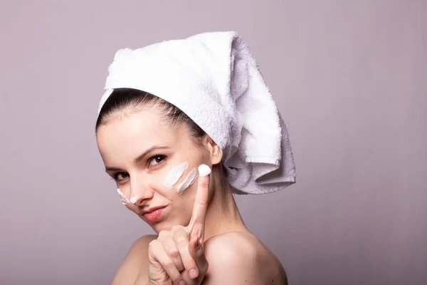 Menina Com Uma Toalha Branca Cabeça Creme Seu Rosto Mão — Fotografia de Stock