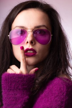 Mor kazaklı kız, mor gözlüklü dudaklarında mor ruj izi olan.