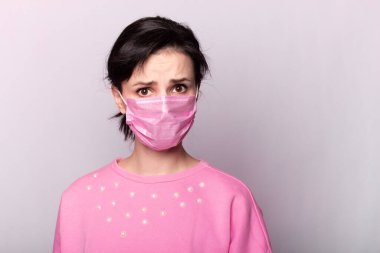 Pembe tıbbi maskeli ve pembe kazaklı kız.
