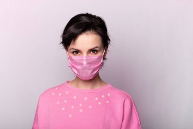 Pembe tıbbi maskeli ve pembe kazaklı kız.