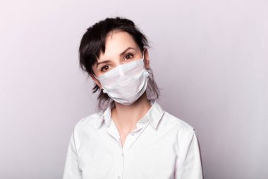 Beyaz gömlekli ve tıbbi maskeli bir kız.