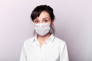 Beyaz gömlekli ve tıbbi maskeli bir kız.