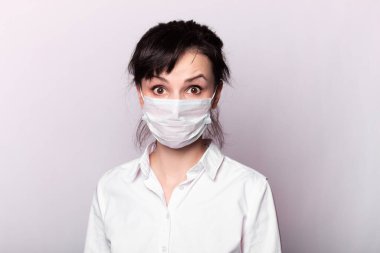 Beyaz gömlekli ve tıbbi maskeli bir kız.