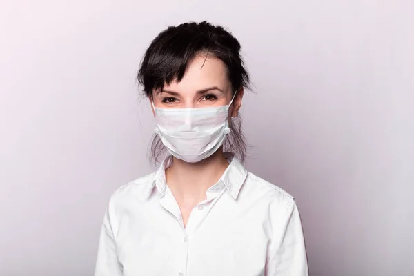 Beyaz gömlekli ve tıbbi maskeli bir kız.