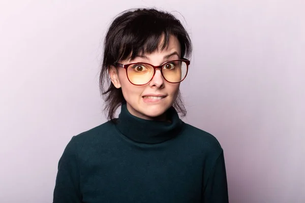 girl in a green turtleneck, glasses, portrait on a gray background