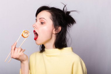 Suşi yiyen ve arka planda yuvarlanan bir kadın