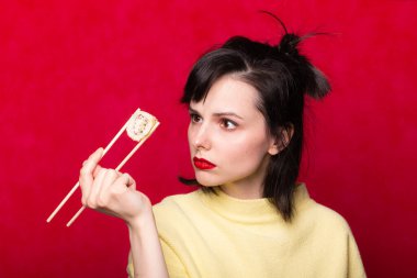 Kırmızı dudaklı bir kadın arka planda suşi yiyor. Asya yemekleri.