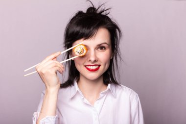 Kırmızı dudaklı beyaz gömlekli kız Asya yemeği yiyor.