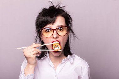 Güzel kız öğrenci elinde çubuklarla Japonya 'da suşi yuvarlıyor.