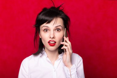 Beyaz gömlekli kız telefonda konuşuyor, kırmızı arkaplan.