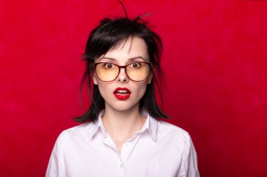 Beyaz gömlekli, kırmızı dudaklı, kırmızı arka planlı bir kadın ofis çalışanı.